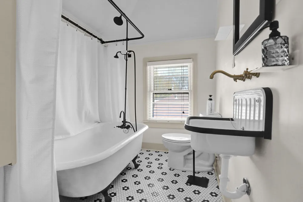 A bathroom with a clawfoot tub and black and white floor tile.