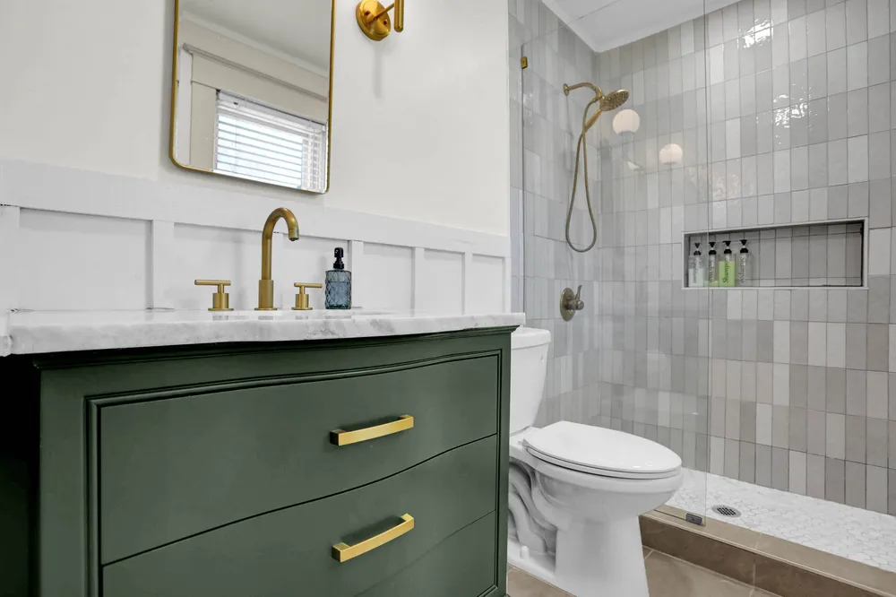A bathroom with a green vanity and a tiled walk-in shower.