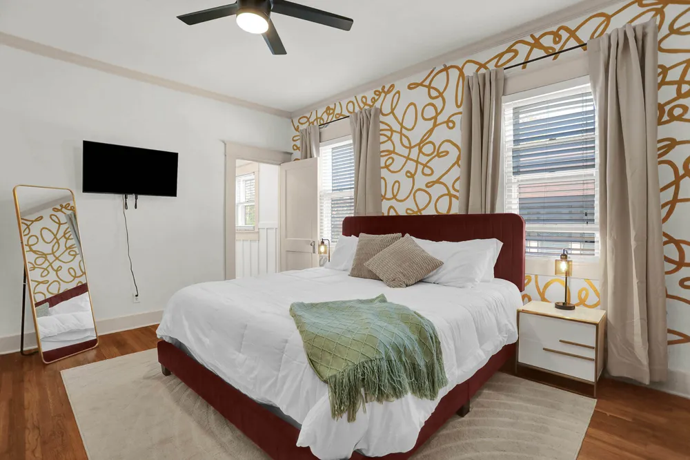 A bedroom with a red headboard and patterned wallpaper.
