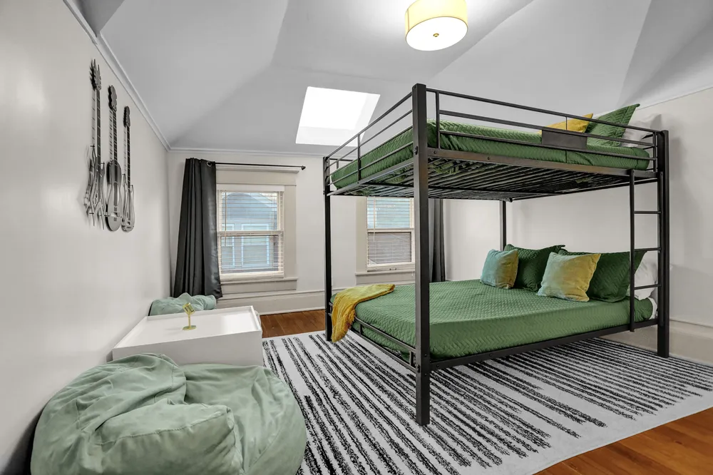 A bedroom with a bunk bed over a larger bed, under a skylight.