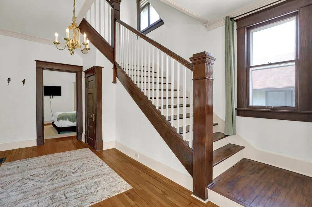 The entry hall and wooden staircase, with a chandelier above.