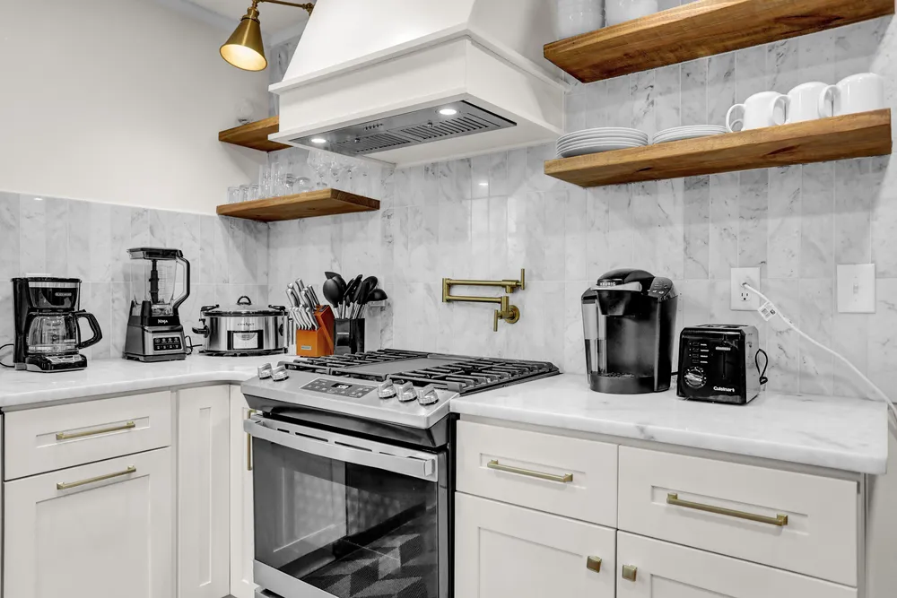 The range, marble backsplash and open shelves with mugs.