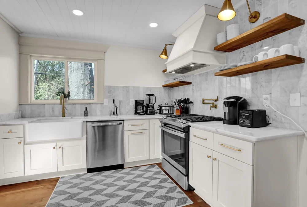The kitchen: white cabinets, open wood shelves and a range.