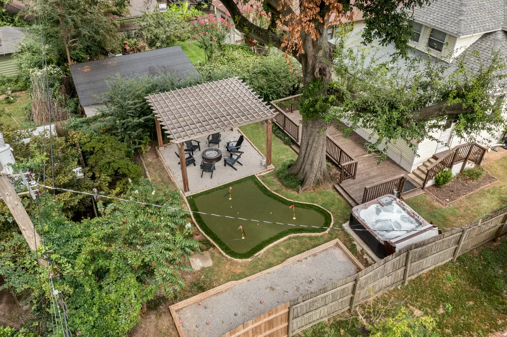The backyard seen from above: pergola, putting green, deck and bocce court inside a wooden fence.
