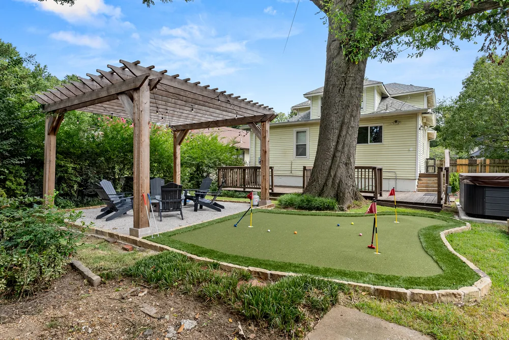 The backyard looking toward the back of the house, with the pergola and putting green.